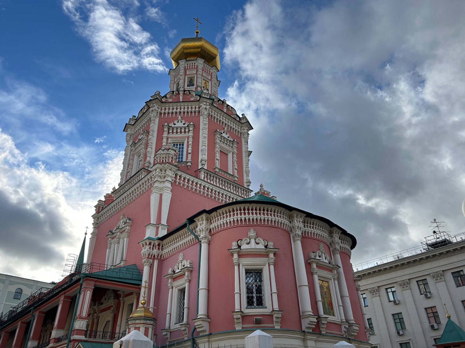 Богоявленский собор в Китай-городе: розовые стены, белый резной декор и золотая глава на фоне облаков