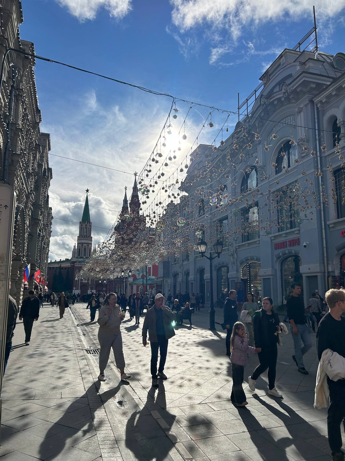 Никольская улица в Москве: гирлянды над пешеходной зоной, вдали башни Кремля и Исторический музей